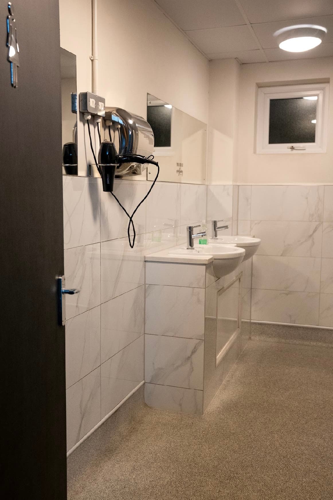 The changing rooms at Next Gen Fight Hub, tiled with sinks, mirrors and hair dryers