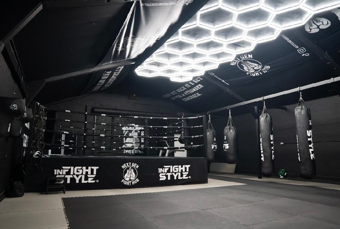 The main training floor at Next Gen Fight Hub, ring on the left and heavy bags on the right under hexagon lights