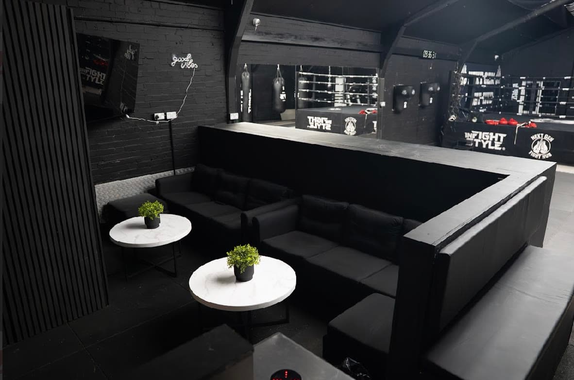 The seating area at Next Gen Fight Hub, black sofas and a good vibes neon sign