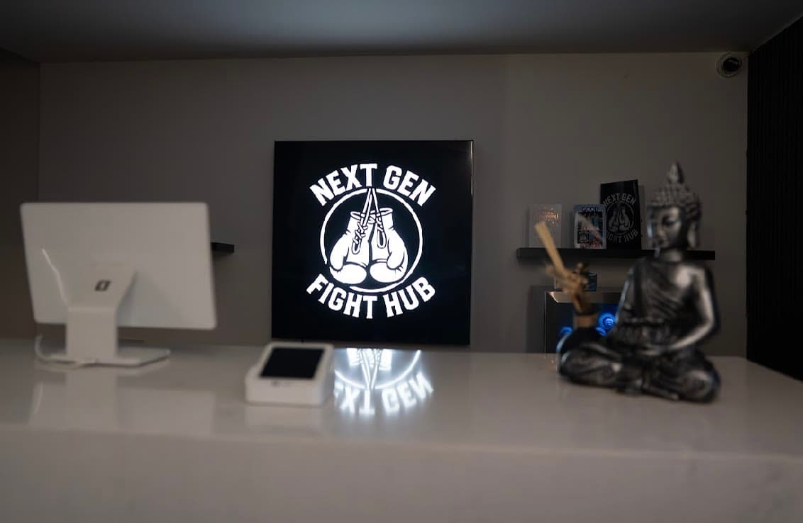 The reception desk at Next Gen Fight Hub with the lit club crest behind it