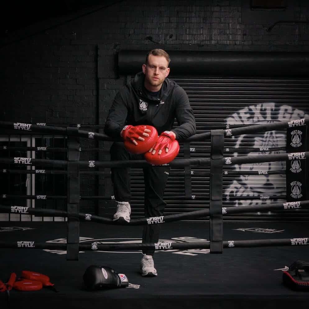 Head coach Hayden in the ring holding the pads