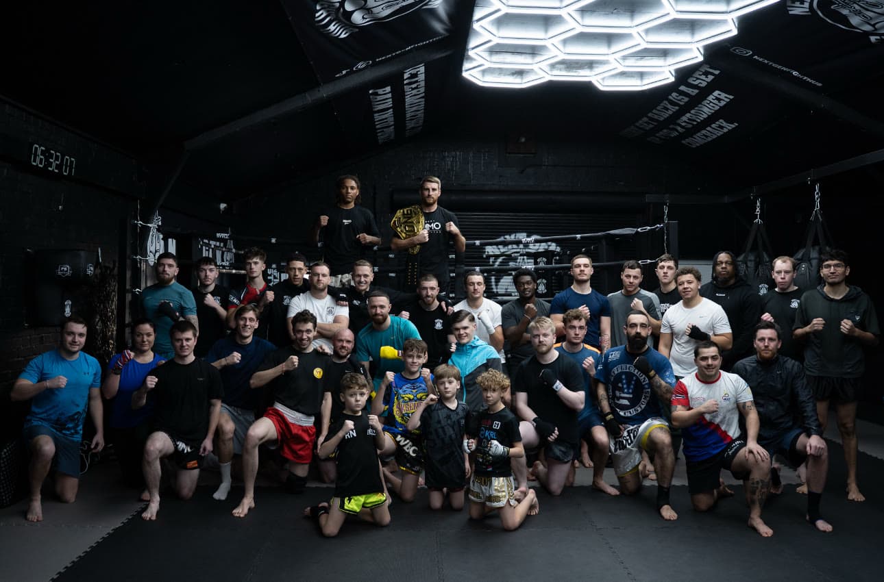 The full Next Gen Fight Hub team, juniors to adults, gathered in the gym in front of the ring