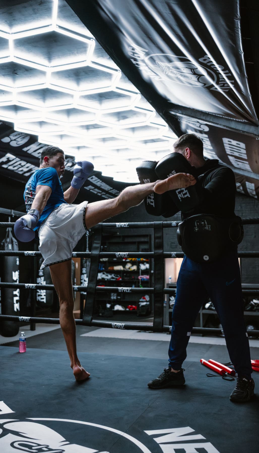 A fighter throwing a high kick onto the pads under the hexagon lights